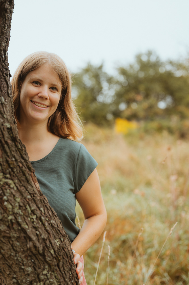 Business Portrait – Frau lächelt hinter Baumstamm, MALEA Fotografie Darmstadt
