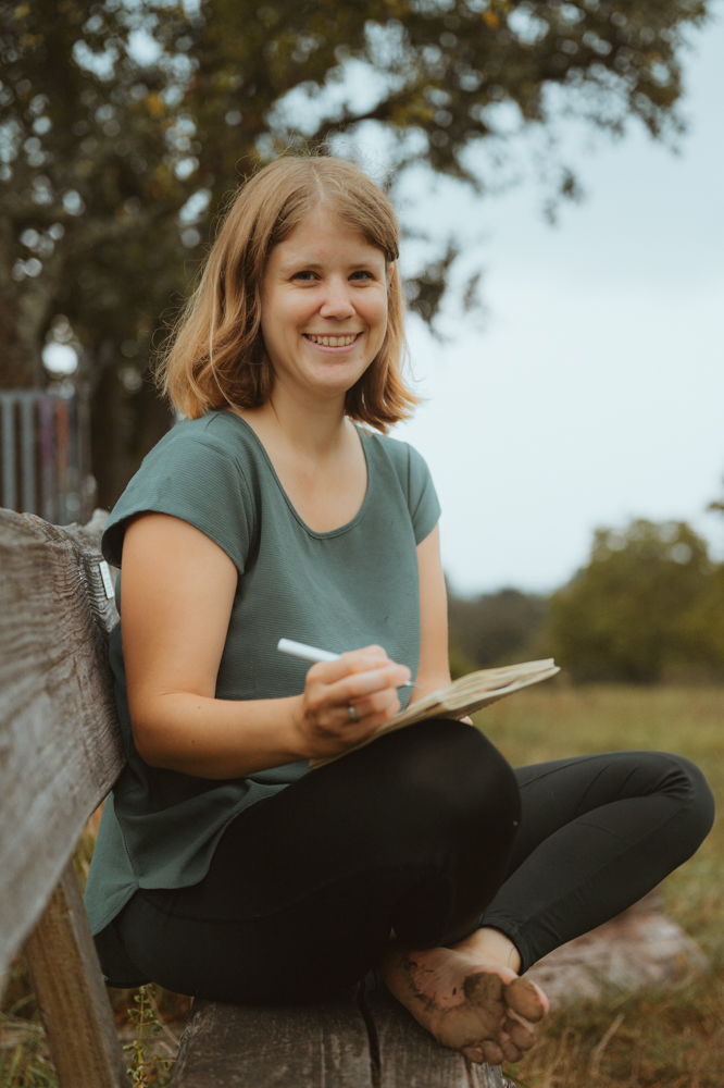 Unternehmerin sitzt barfuß auf Holzbank mit Notizbuch und lächelt – Business Portrait Darmstadt