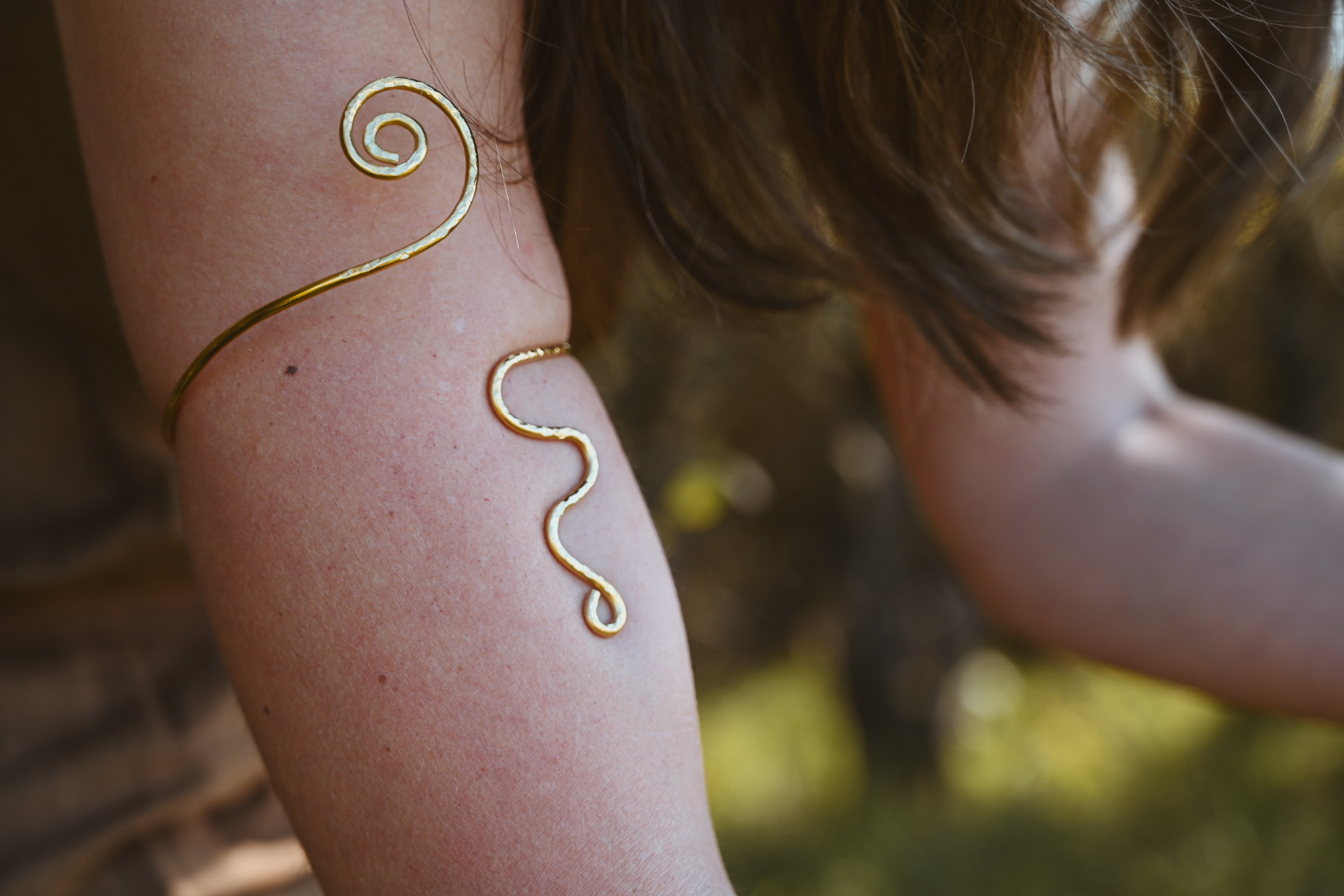Nahaufnahme goldener Schlangenarmreif am Oberarm – Symbol der Häutung und des Wandels, MALEA Fotografie