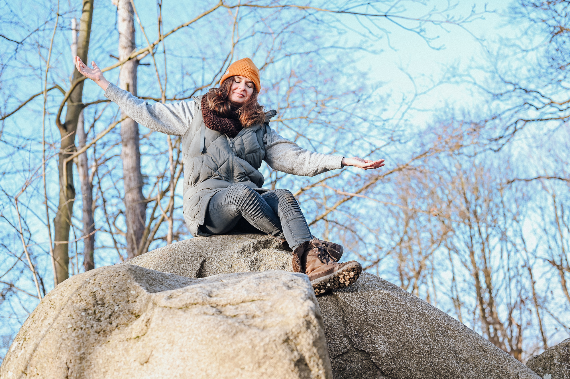 Mareen Zimmermann sitzt mit ausgebreiteten Armen auf einem Felsen in der Kraftruhe Darmstadt – Aufbruch und innere Freiheit