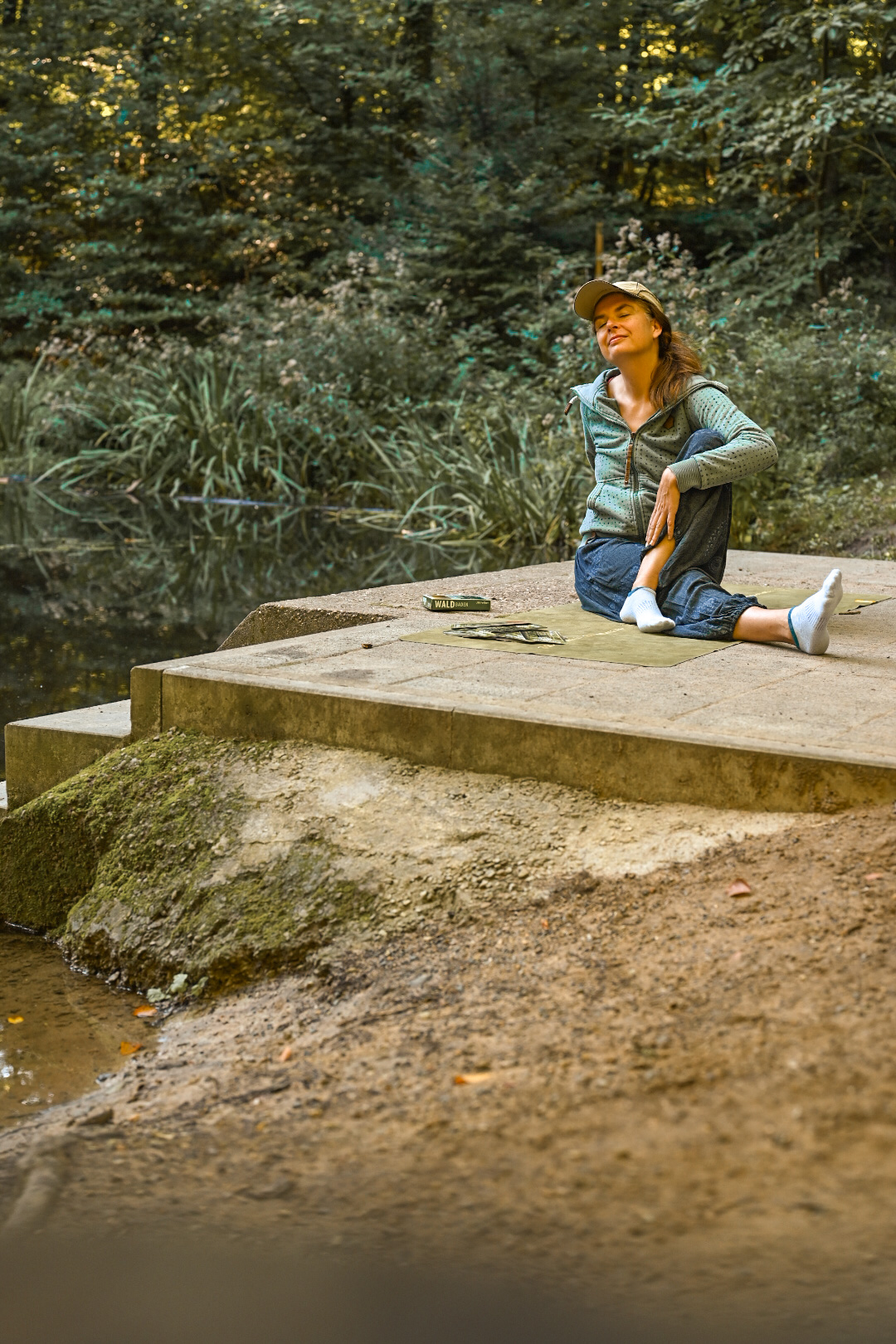 Mareen Zimmermann sitzt entspannt an einem Waldsee, geschlossene Augen, Ruhe und Erdung – Yin Yoga und Natur